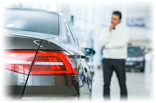 Man standing next to car at dealership