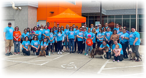 Group of people wearing blue shirts standing in front of Ascentra's home office on a sunny day