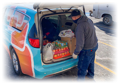 Man in a gray sweatshirt and black hat unloading the trunk of the Ascentra van.